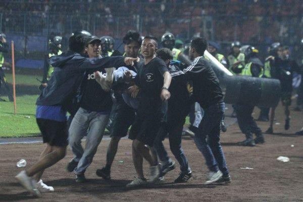 Sejumlah penonton membawa rekannya yang pingsan akibat sesak nafas terkena gas air mata usai pertandingan sepak bola BRI Liga 1di Stadion Kanjuruhan, Malang, Sabtu (1/10).