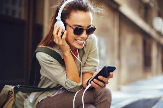 Wanita mendengarkan musik melalui headphone di Jalan