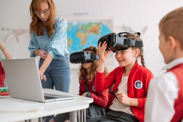 Anak-anak sekolah mengenakan kacamata realitas virtual di sekolah di kelas ilmu komputer. Shutterstock/ Halfpoint.